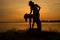 YOGA Silhouette Trainer and woman practicing yoga poses on sunset riverside of nature