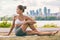 Yoga stretch exercise fit Asian woman stretching lower back for spine health on city outdoor fitness class in park. Seated spinal