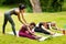 Yoga teacher assisting young woman during outdoor group class at park