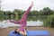 Yoga teacher demonstrates a shoulder stand beside a lake