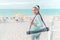 Yoga teacher going to beach with exercise mat to give outdoor yoga or pilates class at hotel resort in tropical