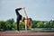 Yoga teacher standing in pose sugarcane, asana ardha chandra chapasana, at city park near the lake, on sunshine morning