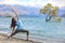 Yoga travel New Zealand. Asian girl practicing yoga at the lone tree in Wanaka lake, NZ. Woman training fitness for a