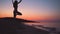 Yoga vrikshasana tree pose by woman in silhouette with sunset sky background
