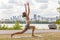 Yoga wellness class outside in city park woman doing high lunge crescent pose on exercise mat outdoors against skyline river