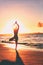 Yoga wellness retreat class on morning sunrise beach landscape. Silhouette of girl standing in tree pose meditation