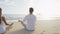 Yoga woman and man meditating in lotus pose beach