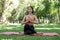 Yoga woman meditation praying outside in city park wellness. Summer exercise lifestyle active young Asian girl