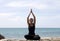 Yoga woman poses on beach near sea and rocks