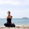 Yoga woman poses on beach near sea and rocks