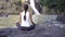 Yoga woman sit in meditation pose near waterfall in Dalat, Vietnam