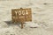 Yoga wooden sign on a sand beach.