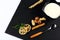 Yoghurt plate, mint leaves, slices of lemon, wheat, nuts, a sticks of cinnamon and a spoon on a black shale board, on a white back