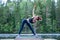 Yogi girl practicing yoga, doing Utthita Trikonasana exercise, extended triangle pose  on the lake. The concept of appeasement,