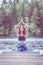 yogi  girl  practicing yoga, sitting in variation of Gomukhasana, Cow Face Posture  on the pier of a beautiful lake. Concept