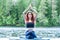 Yogi  girl  practicing yoga, sitting in variation of Gomukhasana, Cow Face Posture  on the pier of a beautiful lake. Concept