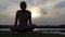 Yogi man sits in a lotus and raises his body at sunset in slo-mo