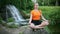 Yogic meditation practice Yogic doing yoga on the rocks against the waterfall