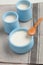 Yogurt in blue pots on gray linen napkin with bamboo spoon