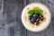 Yogurt with blueberries, granola, above view on rustic dark wood