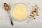 Yogurt in glass bowl, muesli in spoon, scattered granola on table. Top view