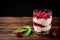 Yogurt with granola, raspberry and raspberry jam on dark wooden background