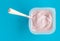 Yogurt in plastic cup close up - Pink yoghurt on blue background