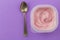 Yogurt plastic cup with strawberry yoghurt on lilac background - overhead image