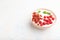Yogurt with raspberry and goji berries in ceramic bowl on white concrete background. Side view, copy space