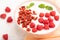 Yogurt with raspberry and goji berries in ceramic bowl on white concrete background. Side view, selective focus