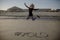 YOLO hashtag written in the sand on the beach and an adult female jumping.