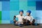 Yong little athletic boys on roller sitting against the blue graffiti wall