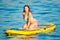 Yong Woman blowing a kiss on a Yellow Sup Paddle Board