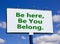 You belong here symbol. Words `be here, be you, belong` on white billboard. Beautiful blue sky. Business, diversity, inclusion,