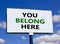 You belong here symbol. Words `you belong here` on white billboard. Beautiful blue sky. Business, diversity, inclusion, belongin