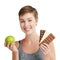 You always have a choice. Studio portrait of a fit young woman deciding whether to eat chocolate or an apple against a