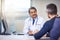 You have a doctor who cares. a cheerful mature male doctor seated at his desk while consulting a patient inside a