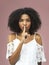 You have to keep it a secret. Studio shot of an attractive young woman posing with her finger on her lip.