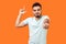 You are loser! Portrait of bossy angry brunette man showing loser gesture and pointing at camera. isolated on orange background