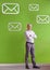 You might want to check your inbox. a mature businessman standing in front of a green wall filled with message symbols.