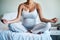 You need all the peace you can get during pregnancy. an unrecognizable pregnant woman practicing yoga inside her bedroom
