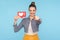 You push network Like button! Portrait of positive fashionably dressed woman with hair bun holding social media heart icon