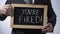 You\'re fired written on blackboard, businessman holding sign, business concept