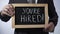 You\'re hired written on blackboard, businessman holding sign, business concept