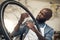 You see a bike, I see greener grass. a young man fixing a wheel at a bicycle repair shop.