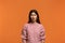 Are you serious. Portrait of shocked stunned beautiful woman in pink sweater, looking dissatisfied and surprised. On orange