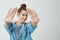 You are very photogenic. Studio shot of creative beautiful female photographer with bun hairstyle, pulling palms towards