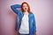 Youg beautiful redhead woman wearing denim shirt standing over isolated pink background confuse and wonder about question