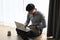 A youn businessman working on his project with laptop while sitting on floor.