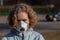 Yound girl with blonde hair with serious face with protective medical mask. Angry look. Ecology and climate disaster concept. Copy